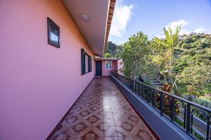 A corridor with patterned flooring leading to a balcony with a view of a hillside. - Vivenda Paz Lobo by Your Key (Santa Cruz)