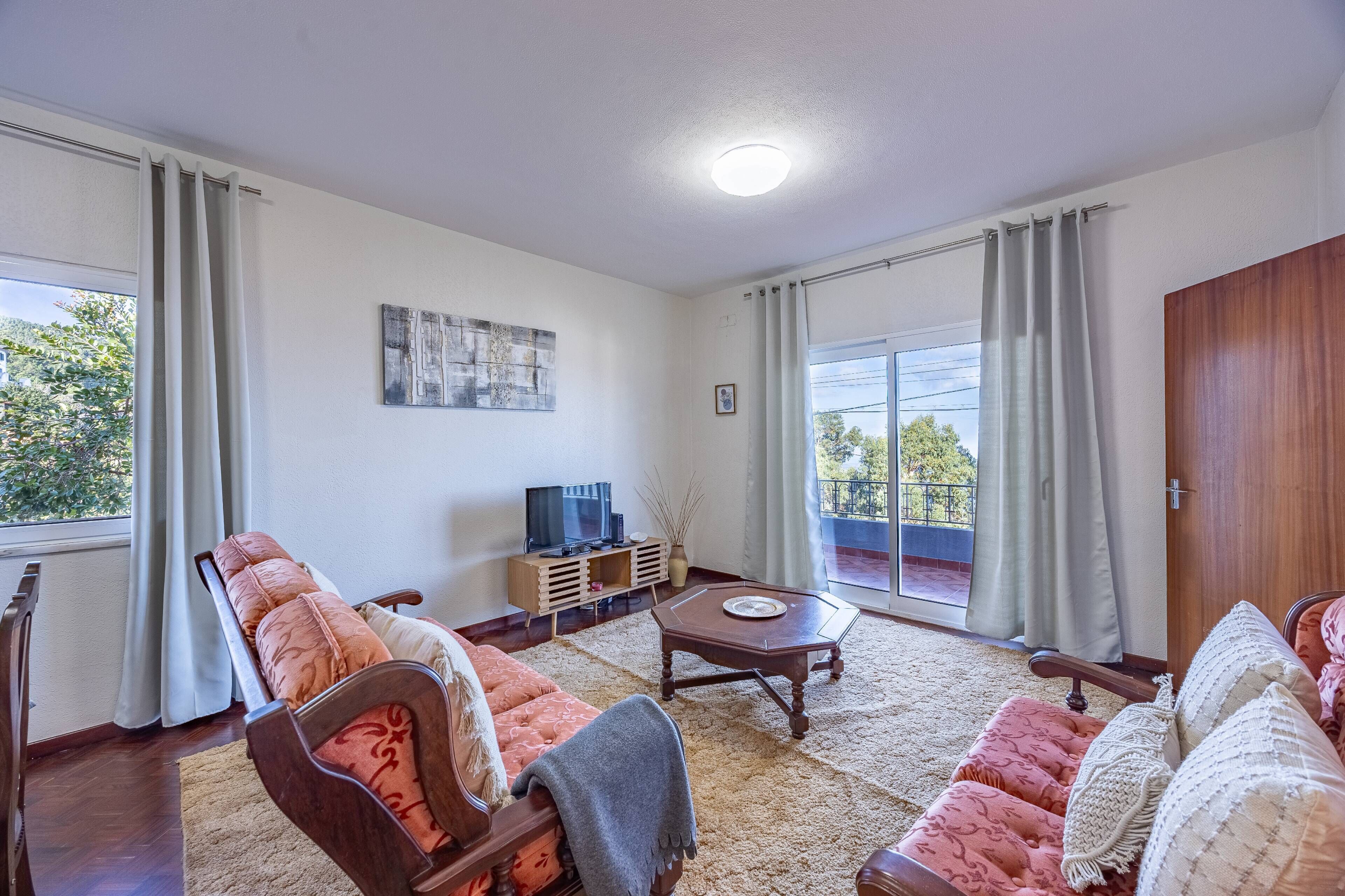 A living room with a sofa set, a coffee table, a television, and a painting on the wall.