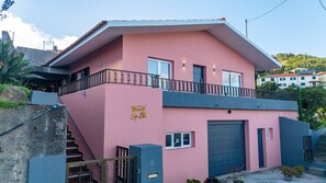 A pink building with a balcony, a garage, and a staircase. - Vivenda Paz Lobo by Your Key (Santa Cruz)