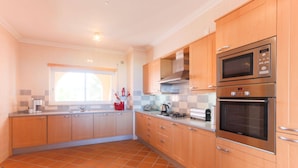 A kitchen with wooden cabinets, a tiled floor, a window, and a built-in oven.