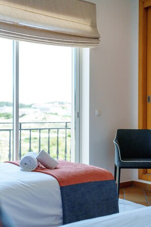 A hotel room with a bed, a window with a view, a chair, and a door. - Horizon Retreat, Sea View A12 (Óbidos)