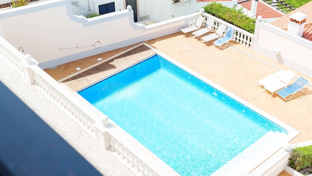 En rektangulær swimmingpool med en fliseterrasse hele vejen rundt.