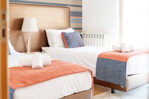 A hotel room with two beds, a bedside lamp, a radiator, and a window with curtains. - Horizon Retreat, Sea View A12 (Óbidos)