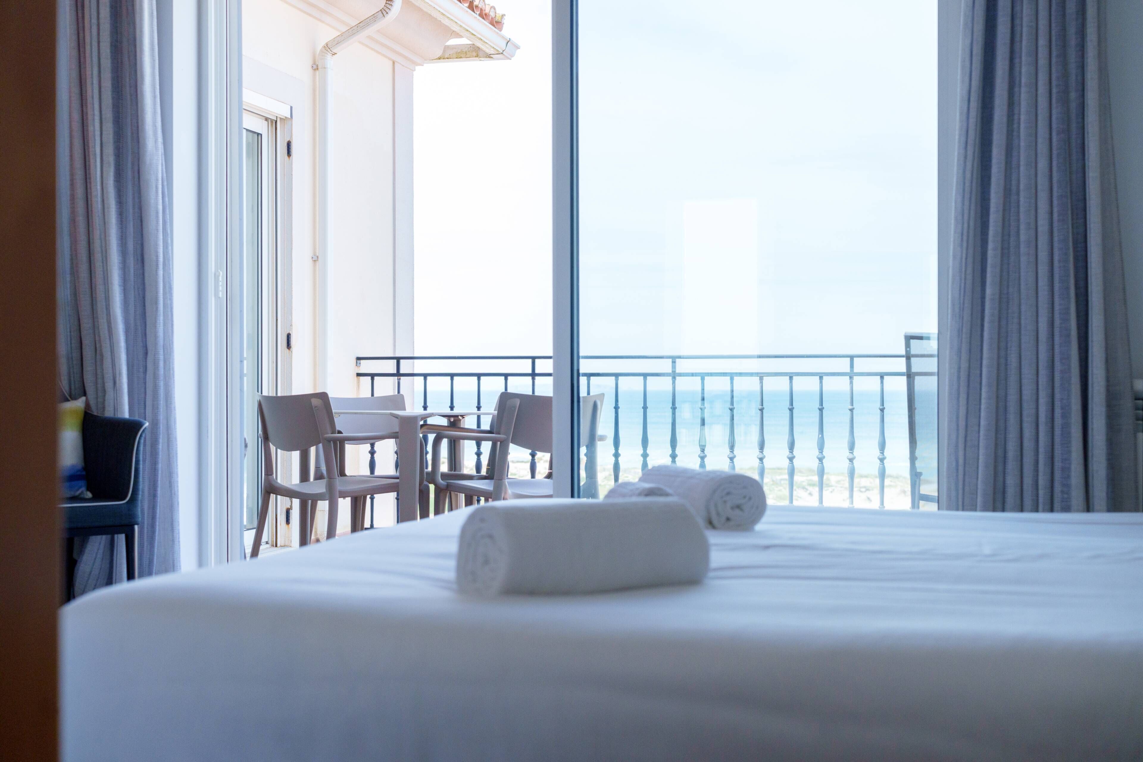 Une chambre d’hôtel avec un lit, deux chaises, une table et une vue sur la mer.