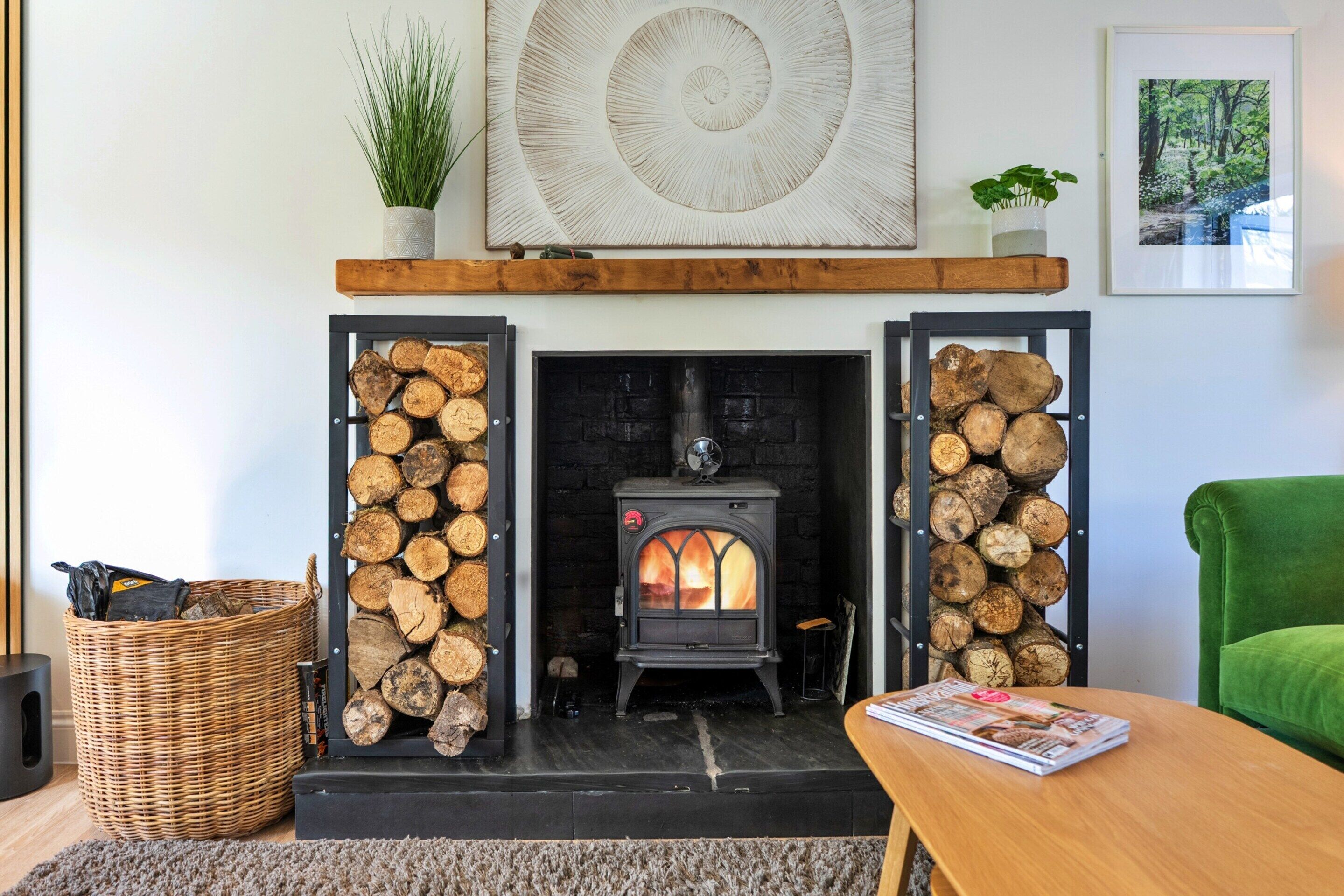 A living room with a fireplace, a green armchair, a wooden table, and a magazine.