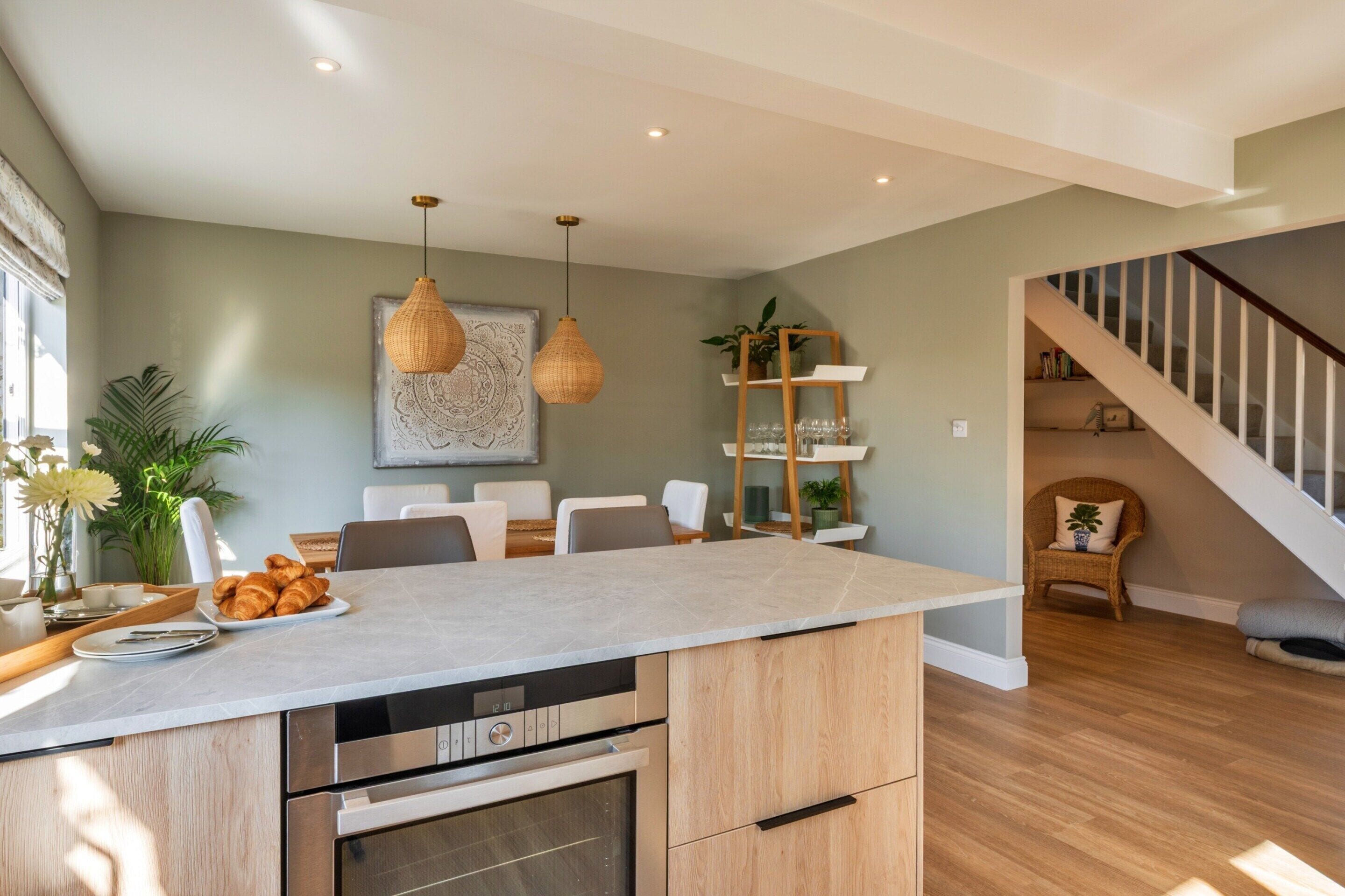 A modern kitchen with a central island, built-in oven, and pendant lighting.
