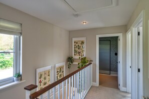 A hallway with a wooden railing, a window with blinds, and a door with a speckled wall. - Luxury Lodge With Hot Tub (Camelford)
