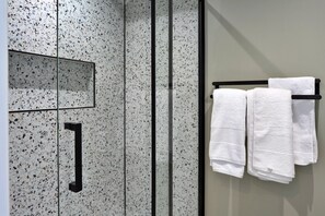 A bathroom with a glass shower door, a towel rack with folded towels, and a rectangular mirror. - Luxury Lodge With Hot Tub (Camelford)