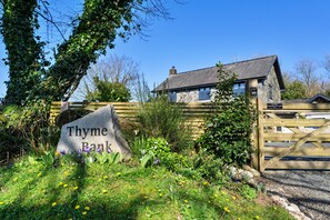 A stone sign with 'Thyme Bank' inscribed, a wooden gate, and a stone house with a grey roof. - Luxury Lodge With Hot Tub (Camelford)