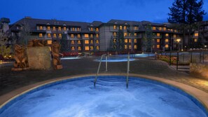 Ein Hotel mit mehreren Stockwerken, Außenwhirlpools und Steinbärenstatuen.