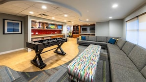 Ein modernes Wohnzimmer mit einem Kicker, einer Couch und einer bunten Bank.