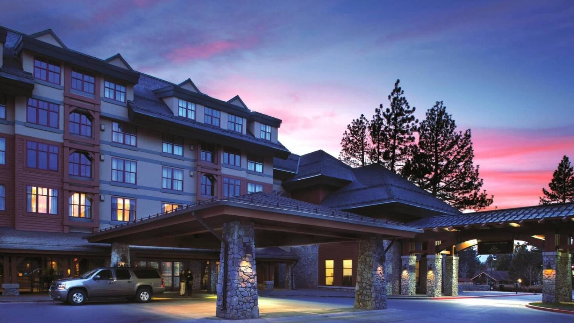 A multi-story hotel with a covered entrance and stone pillars.