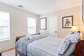 A bedroom with a bed, two windows, a door, and a wall-mounted lamp. - Lake Front! Hot Tub, Fire Pits, Game Room (East Stroudsburg)