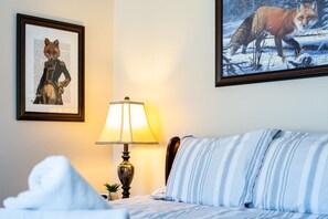 A bedroom with a bed, a lamp, a framed picture of a fox, and another picture of a fox in a snowy landscape. - Lake Front! Hot Tub, Fire Pits, Game Room (East Stroudsburg)