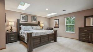 A bedroom with a large bed, two bedside tables, a window with blinds, and a skylight. - Lake Front! Hot Tub, Fire Pits, Game Room (East Stroudsburg)