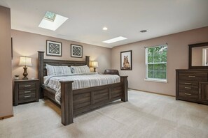A bedroom with a large bed, two bedside tables, a window with blinds, and a skylight. - Lake Front! Hot Tub, Fire Pits, Game Room (East Stroudsburg)