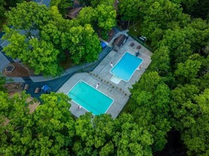 An aerial view of a property with two swimming pools surrounded by dense green trees. - Lake Front! Hot Tub, Fire Pits, Game Room (East Stroudsburg)