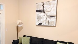 Een woonkamer met een modulaire bank, een vloerlamp en een abstract kunstwerk aan de muur.