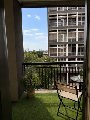 A balcony with artificial grass, a potted plant, and a foldable chair. - Luxury Stay Near NRG Stadium, Downtown & Galleria (Houston)