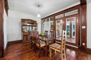 A dining area with a wooden table and chairs, a wooden cabinet, and a large window with a view.
