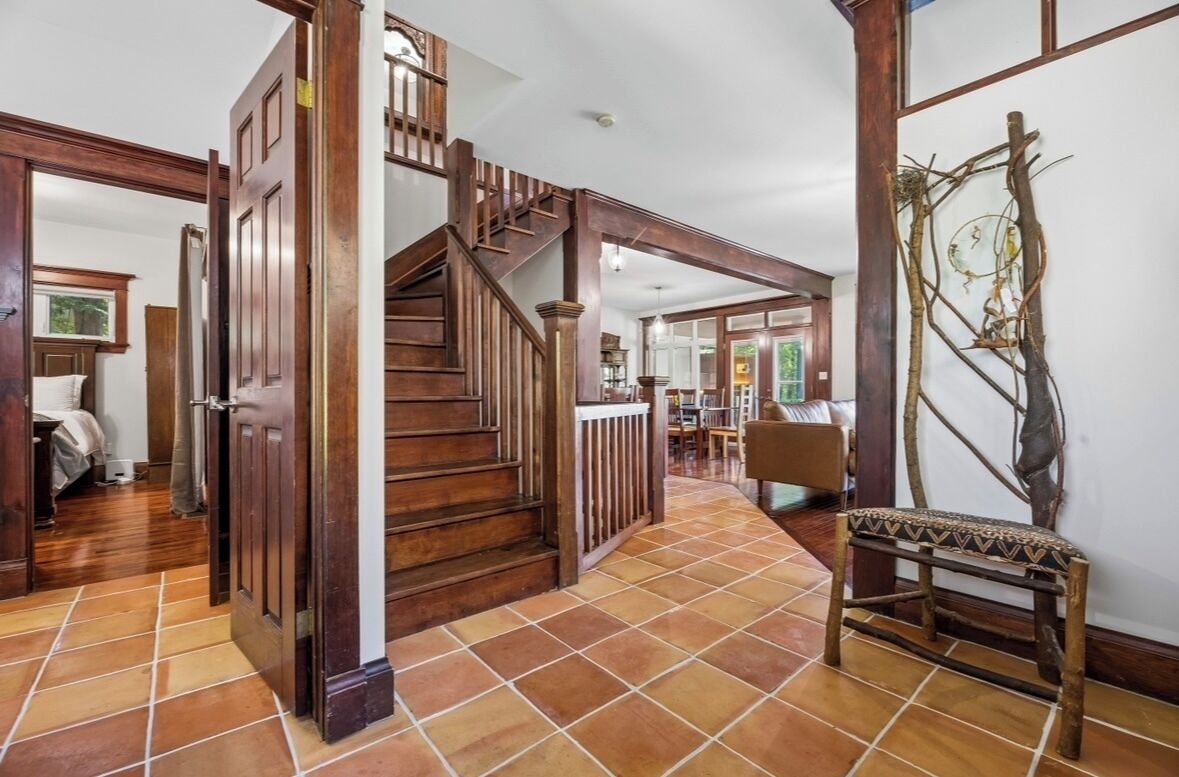 Un escalier avec des rampes en bois menant à l’étage supérieur, un banc et un élément décoratif fixé au mur.