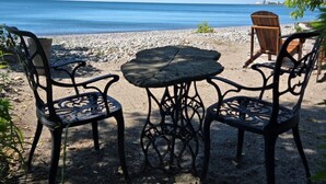 Een zitgedeelte aan het strand met een tafel en stoelen, met uitzicht op zee.