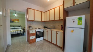 A compact kitchen with a refrigerator, stove, sink, and cabinets. - Dimitra's Guesthouse - Family home with Garden and Gazebo (Loutraki)