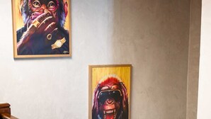 Una scala con balaustre in legno e tre opere d'arte appese al muro.