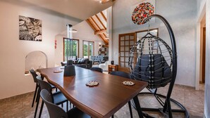 Zona pranzo con tavolo in legno, sedie e una sedia amaca.