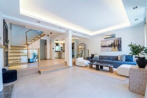 A modern living room with a sofa, coffee table, and a staircase leading to another room. - Luxury Renovated New Villa in the heart of Kalkan (ANTALYA)