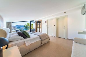 A modern hotel room with a large bed, a seating area, and a balcony with a scenic view. - Luxury Renovated New Villa in the heart of Kalkan (ANTALYA)