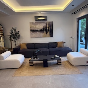 A modern living room with a sectional sofa, a coffee table, and a large abstract painting on the wall.