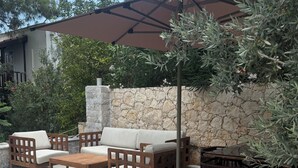 An outdoor seating area with a stone wall, a pool, and a pergola. - Luxury Renovated New Villa in the heart of Kalkan (ANTALYA)