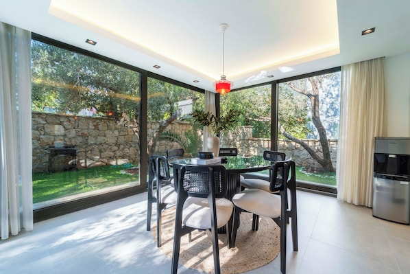 A modern dining area with a round table, chairs, and a red pendant light.