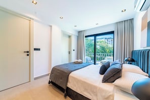 A modern bedroom with a large bed, a view of the outdoors, and a balcony.
