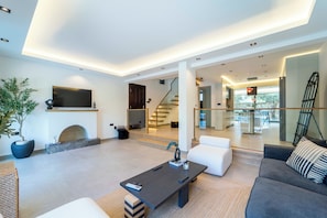A modern living room with a fireplace, a flat-screen TV, a sofa, and a coffee table. - Luxury Renovated New Villa in the heart of Kalkan (ANTALYA)