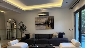 A modern living room with a sectional sofa, a coffee table, and a large window. - Luxury Renovated New Villa in the heart of Kalkan (ANTALYA)