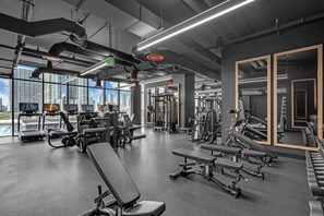 Ein modernes Fitnessstudio mit unterschiedlichen Trainingsgeräten, großen Fenstern und Blick auf die Stadt.