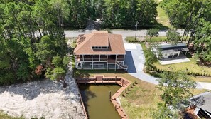 A two-story house with a covered porch and a small pond. - Brand New Beautiful House on the Water in Timber Ridge (Pass Christian)