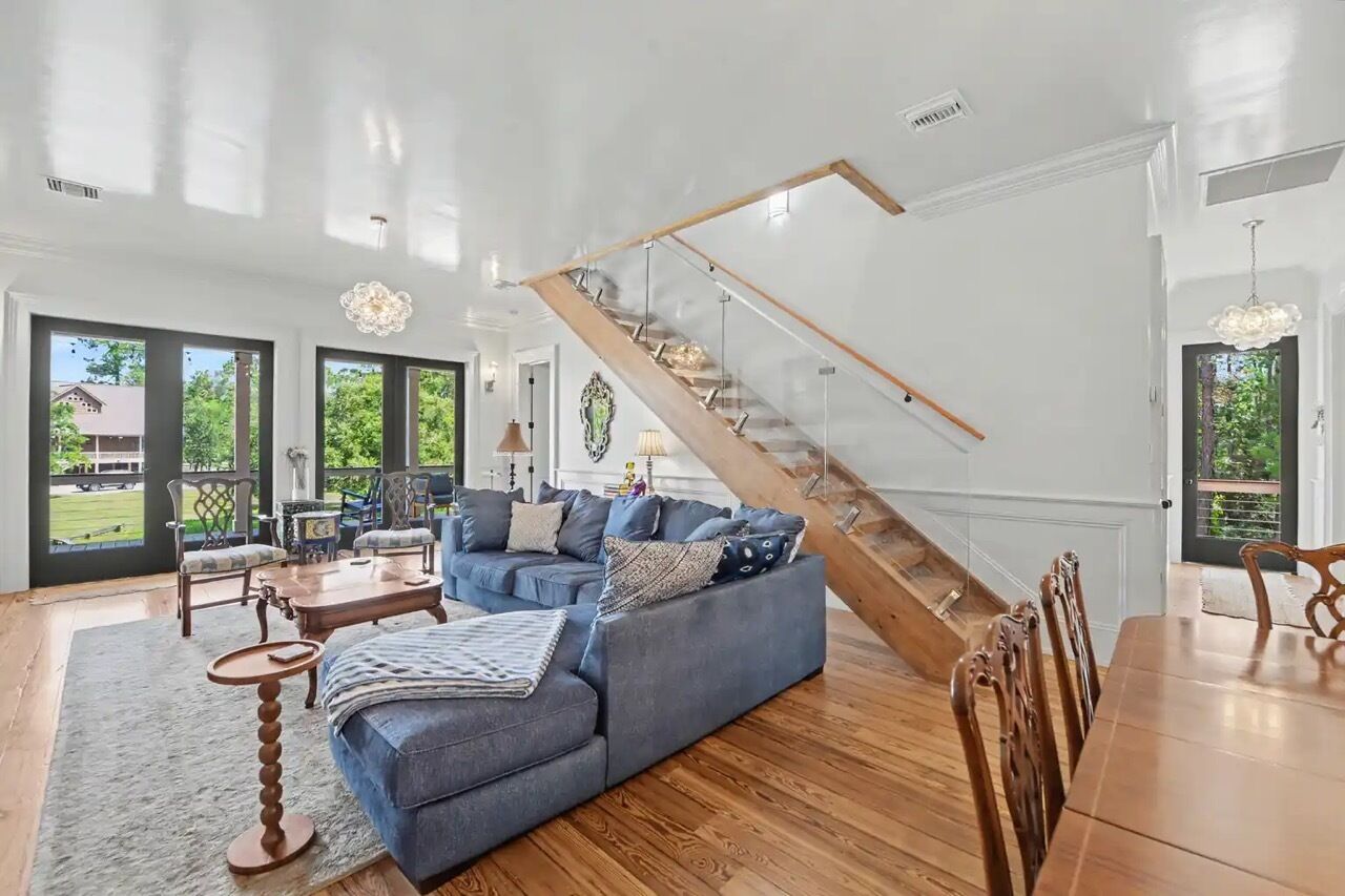 Un salon spacieux avec un canapé bleu, une table à manger en bois et un escalier.