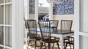 A dining area with a table and chairs, a chandelier, and patterned wallpaper. - Blue Chestnut-Westside Paso Getaway (Paso Robles)
