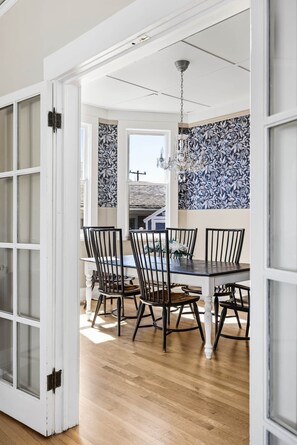 A dining area with a table and chairs, a chandelier, and patterned wallpaper. - Blue Chestnut-Westside Paso Getaway (Paso Robles)