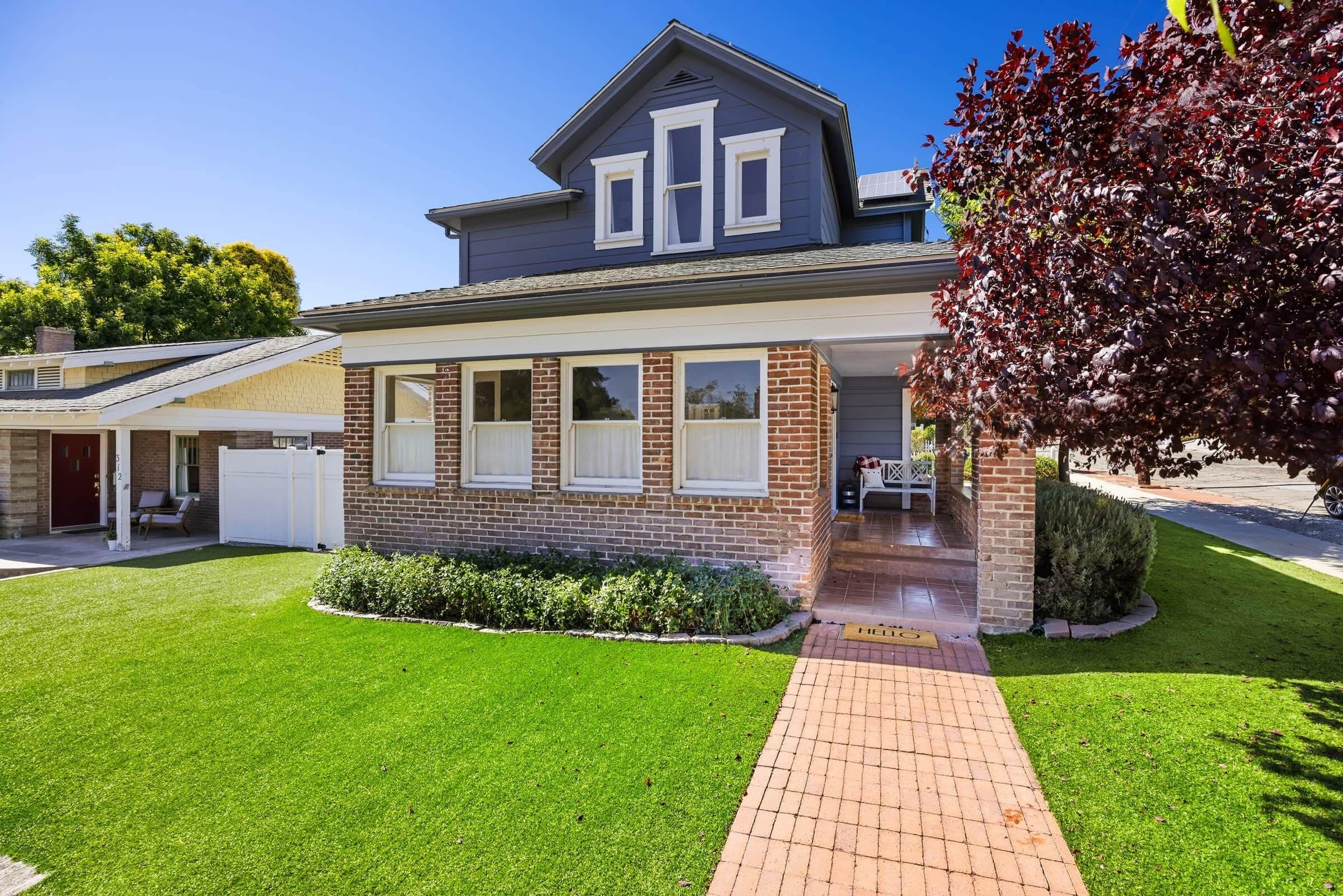 A two-story house with a brick facade, a covered porch, and a well-maintained lawn.