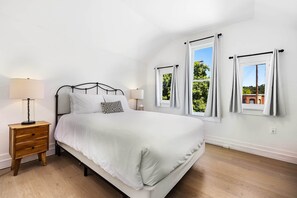 Ein Schlafzimmer mit einem Bett, Nachttischen und Fenstern.