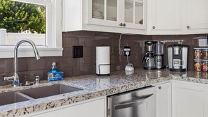 A modern kitchen with a granite countertop, stainless steel appliances, and a window with a view of greenery. - Blue Chestnut-Westside Paso Getaway (Paso Robles)