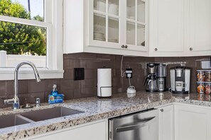 A modern kitchen with a granite countertop, stainless steel appliances, and a window with a view of greenery. - Blue Chestnut-Westside Paso Getaway (Paso Robles)