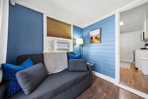 A room with a grey sofa, blue walls, a window with blinds, a lamp, and a painting. - Chestnut Cottage- Cozy Cottage for Two! (Paso Robles)