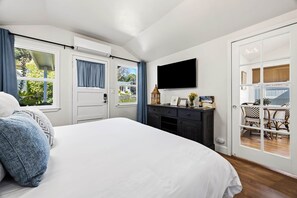 A bedroom with a bed, a dresser, a television, and a view of the outdoors. - Chestnut Cottage- Cozy Cottage for Two! (Paso Robles)