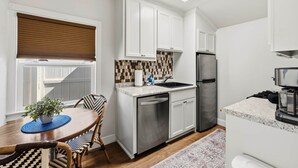 A modern kitchen with white cabinetry, a stainless steel refrigerator, and a coffee machine. - Chestnut Cottage- Cozy Cottage for Two! (Paso Robles)