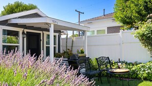 A covered patio area with a white fence, outdoor seating, and a row of lavender plants. - Chestnut Cottage- Cozy Cottage for Two! (Paso Robles)